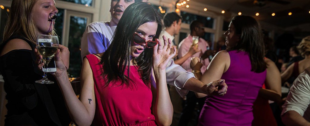 A girl wearing sunglasses as she dances on the dance floor at a fun wedding