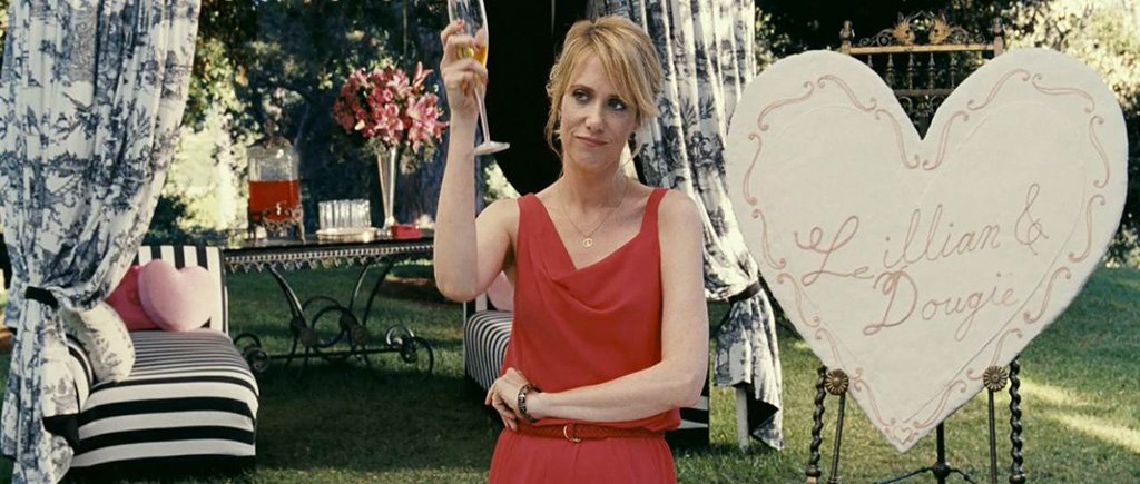 Lillian from Bridesmaids movie playing bridal shower games next to a giant cookie