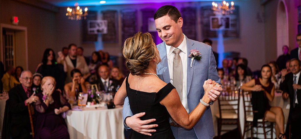 a mother and son doing a dance together at a wedding reception.