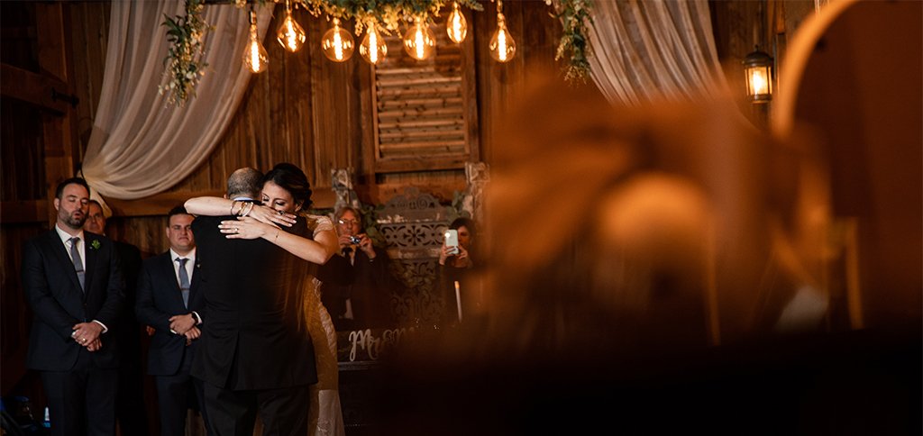 A bride hugging her dad after doing the father daughter dance at the wedding reception. They danced to two of their favorite songs.