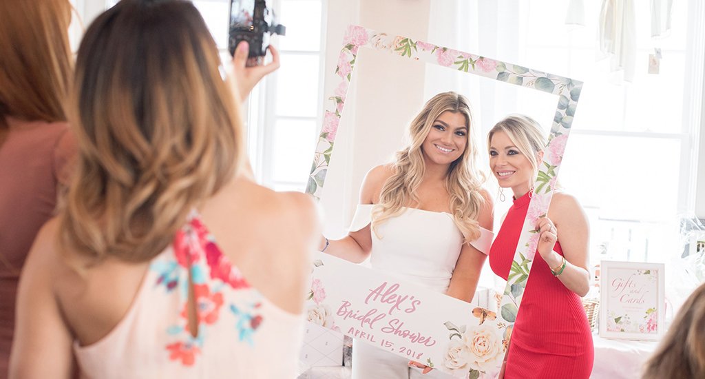 A bride and friend posing for photos at a bridal shower. Made for the what is a bridal shower post.