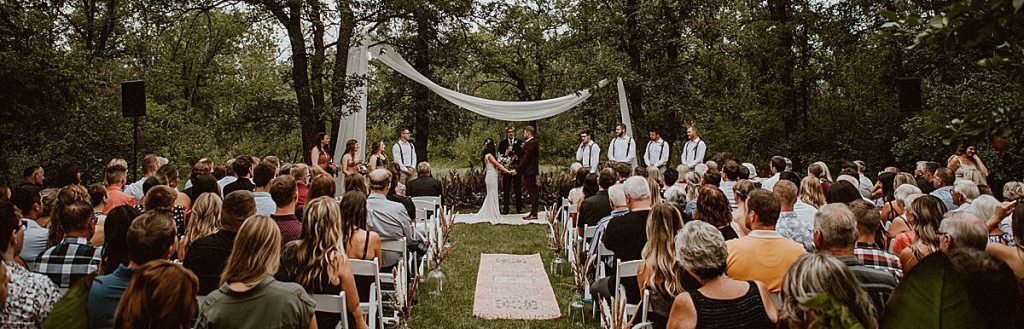 A wedding ceremony taking place in a backyard. This is a wide angle view of all the guests