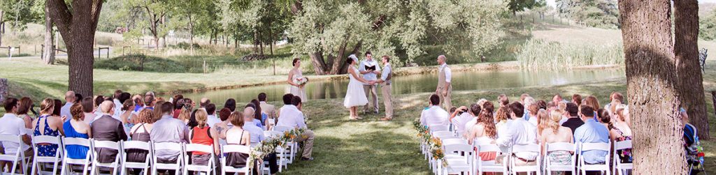 a backyard wedding ceremony taking place near a pond