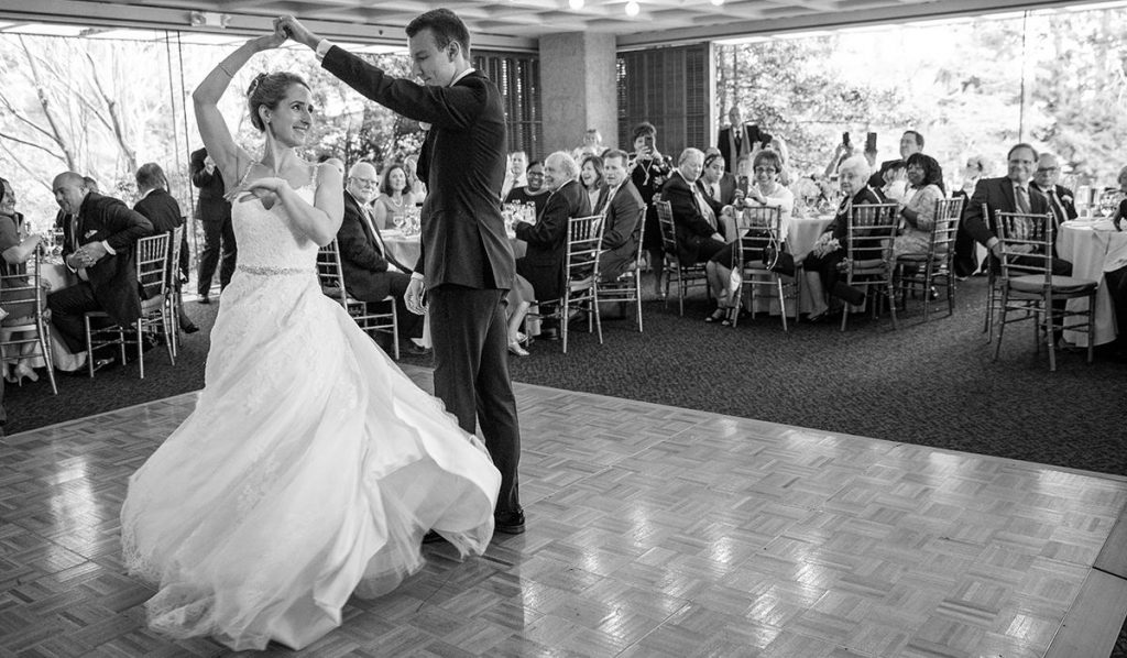 a groom spinning the bride on the dance floor during their first dance. They are dancing to a Dean Martin song