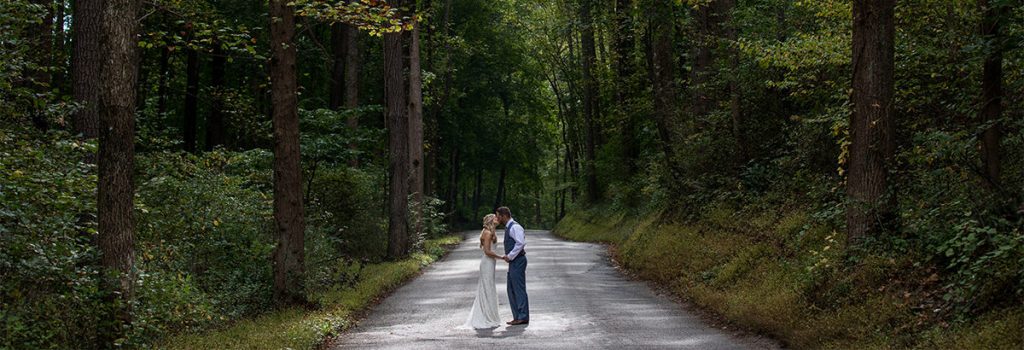 A bride and groom kissing in the middle of the road at their small micro wedding