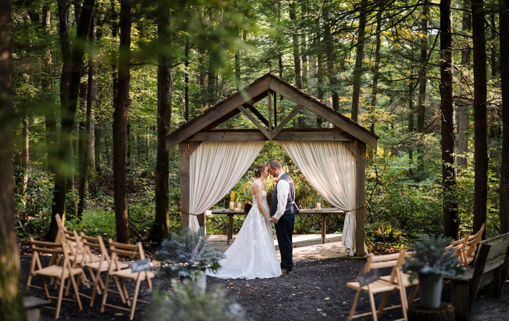 A bride and groom standing forehead to forehead at their micro wedding in the forrest.