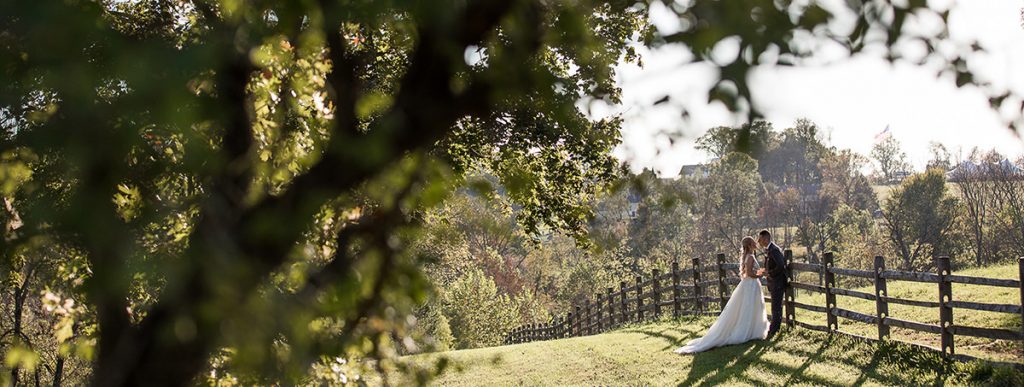 A bride and groom standing near a fence.