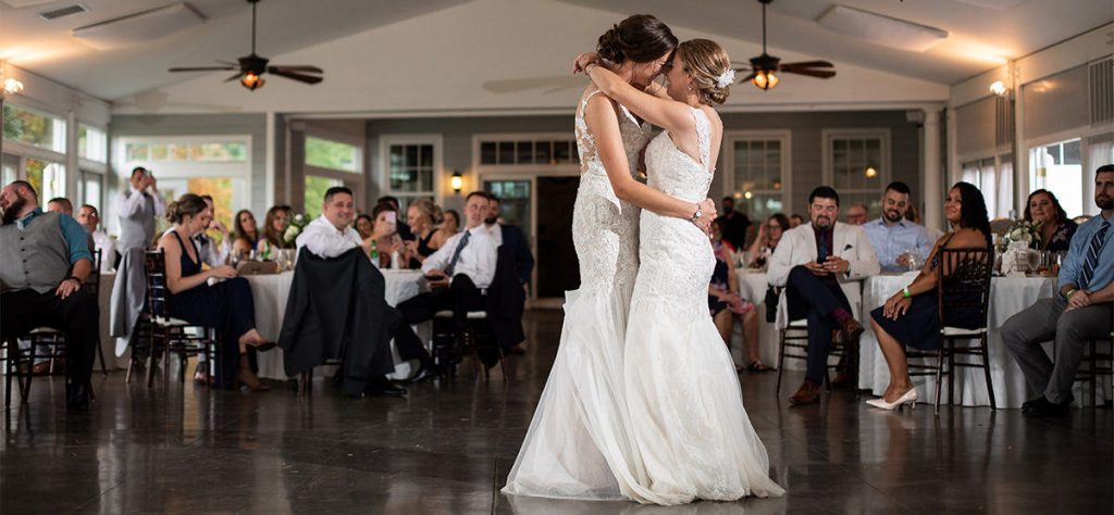 Two brides doing their first dance at their wedding reception.