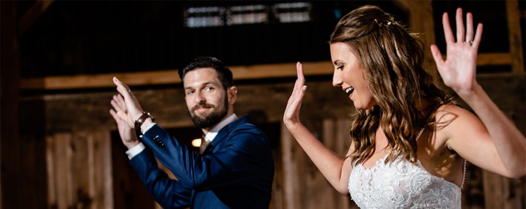 A bride and groom doing a fun dance at their wedding. It is their first dance and they are dancing to their favorite songs.