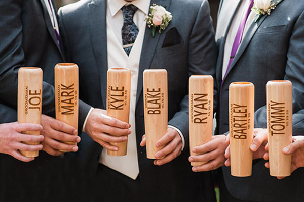 a photo of groomsmen holding baseball bat mugs that were given to them as a gift from the groom.