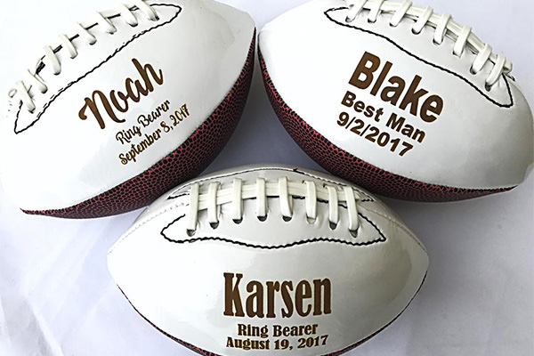3 footballs that are personalized from the groom to the ring bearers at a wedding