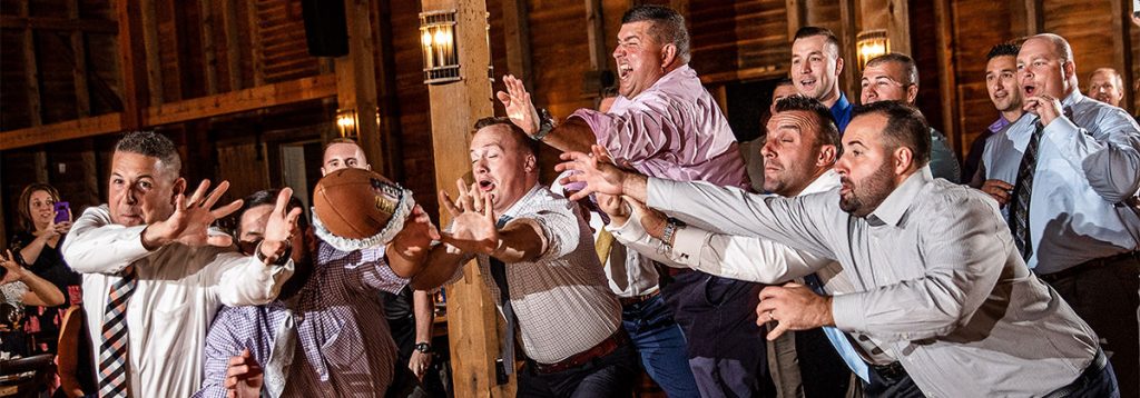 A bunch og guys diving to catch the garter that was tossed by the groom. The DJ was playing a funny garter removal and toss songs
