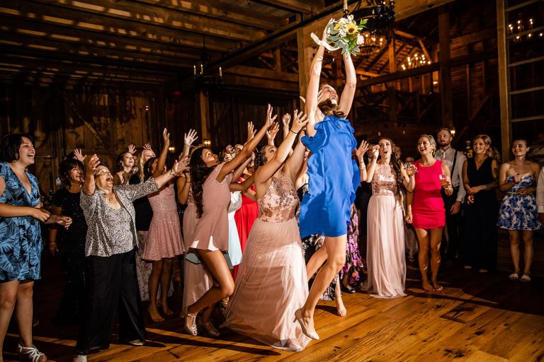 A wedding guest jumping high in the air to catch the bridal bouquet after the bride tossed it