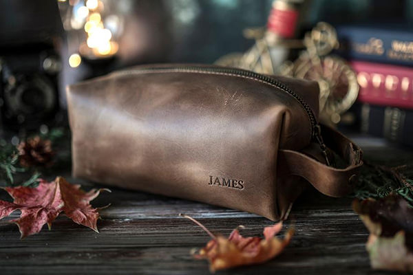 a brown leather shaving kit sitting on a table