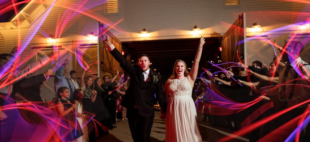 A bride and groom doing a wedding reception exit with glow sticks