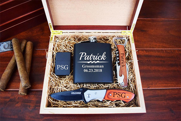 A photo of a gift box containing a flask, lighter, corkscrew, and knife for the groomsmen at a wedding.