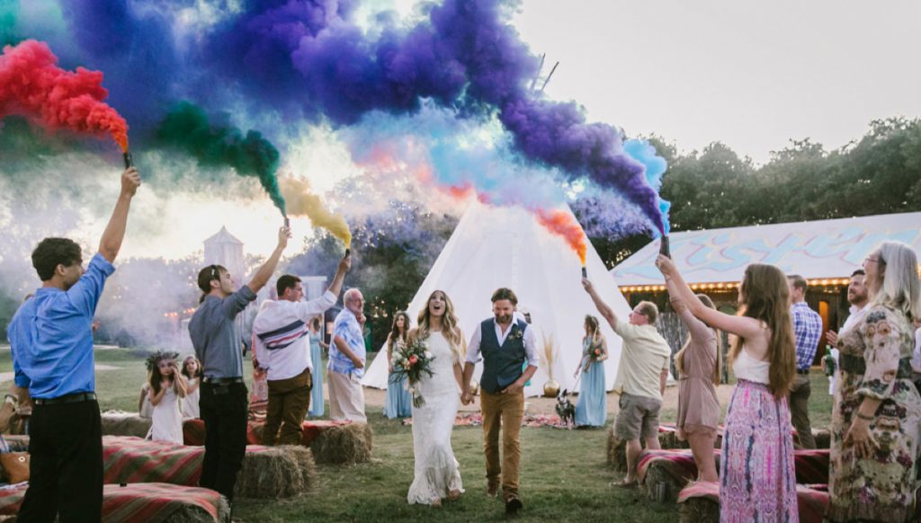 A bride and groom using smoke bombs for the wedding ceremony exit