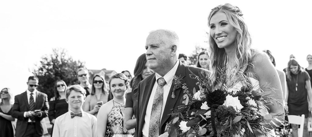 A bride and her father walking down the aisle at the wedding ceremony processional