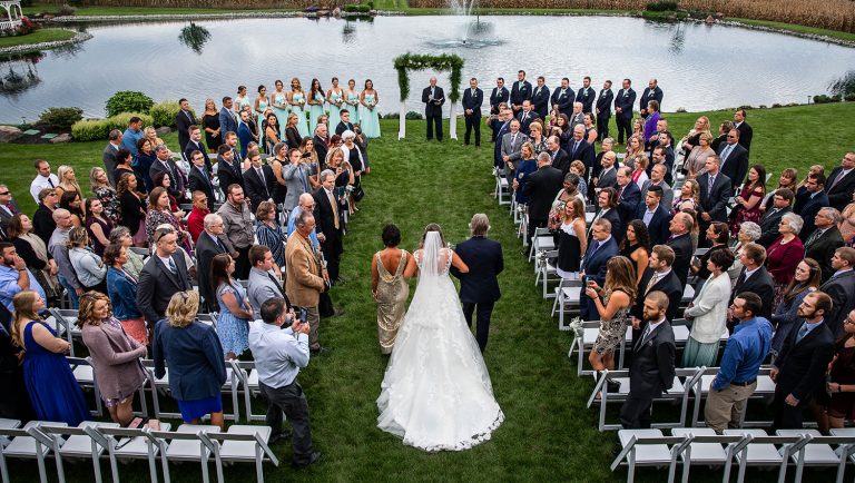 The bride being walked down the aisle by her mom and dad. They are walking in to the bride's favorite song