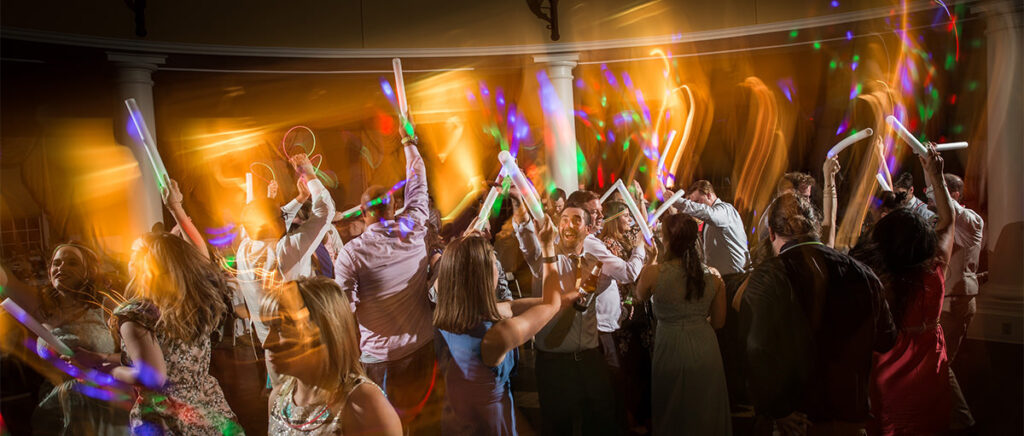 Wedding guests dancing at the reception with glow sticks.