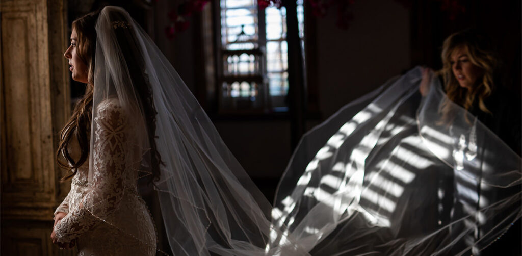 The bride's mom putting the wedding veil on the bride.