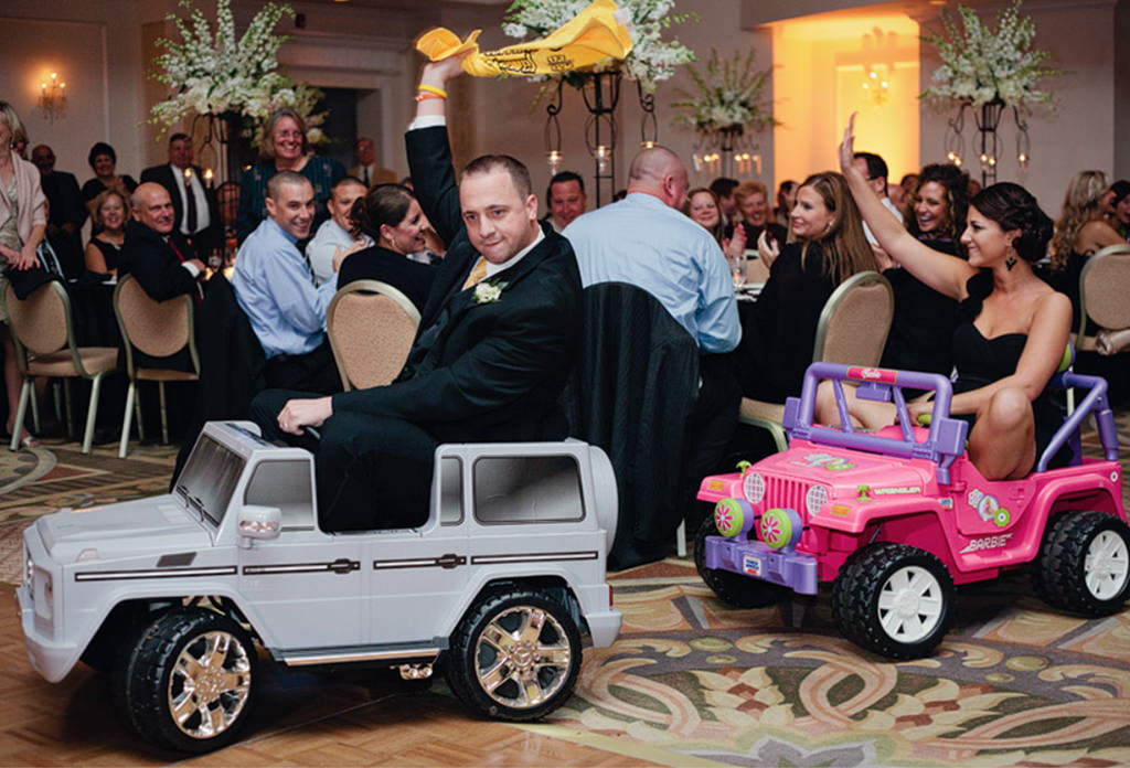 groomsmen and bridesmaid riding into wedding reception on ride on trucks.