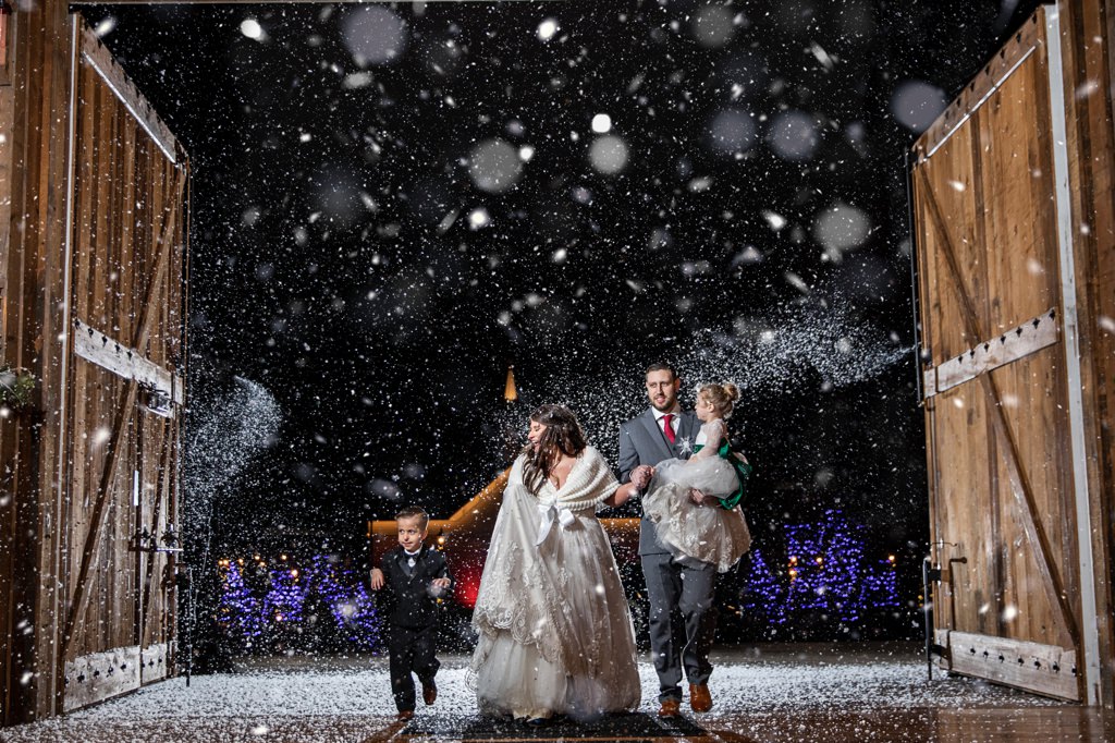 A bride and groom entering the reception under fake snow. This is such a great bridal party entrance idea for a winter wedding.