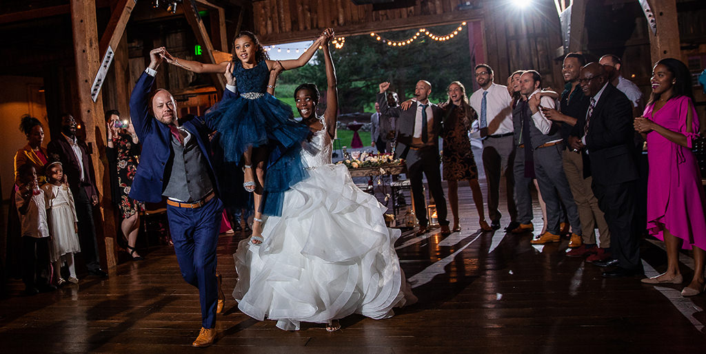 A bride and groom carrying their daughter into the wedding reception for the big entrance
