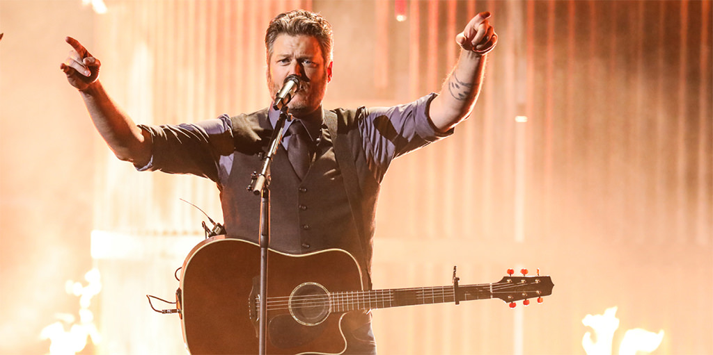 A picture of blake shelton singing a song while holding his guitar. This is for the article called best country songs for wedding.