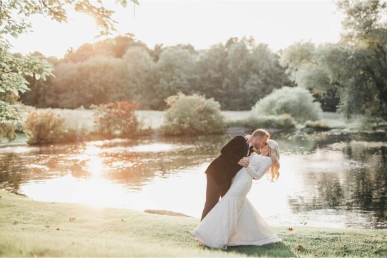 A groom dipping the bride near a pond