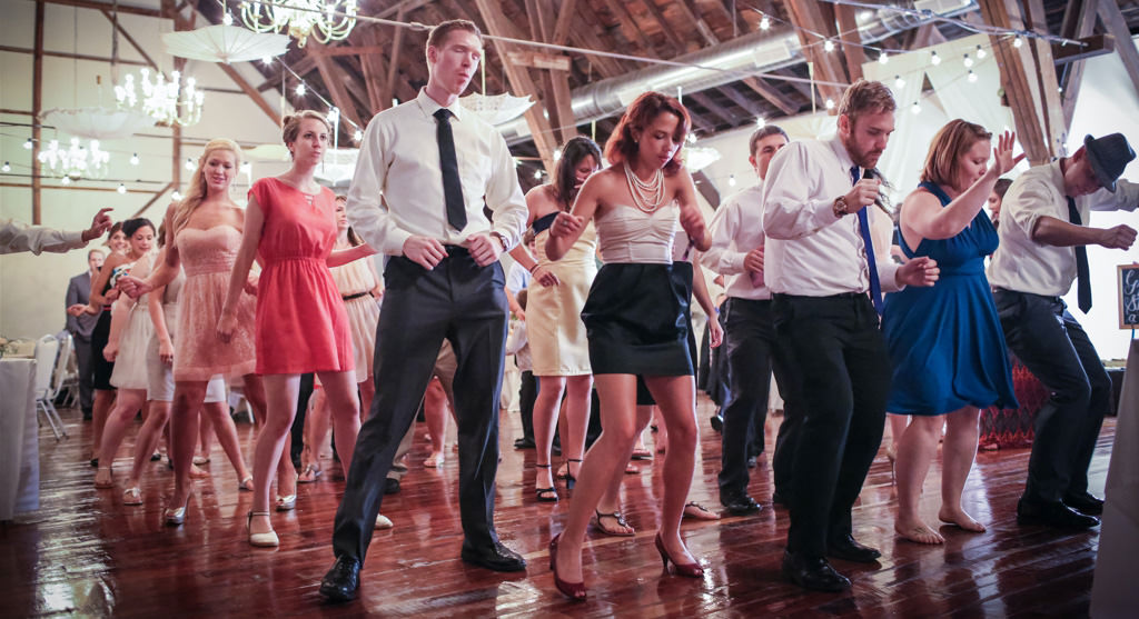 Wedding guests doing the Cha Cha Slide at a wedding reception. This is for the article called wedding group dance songs