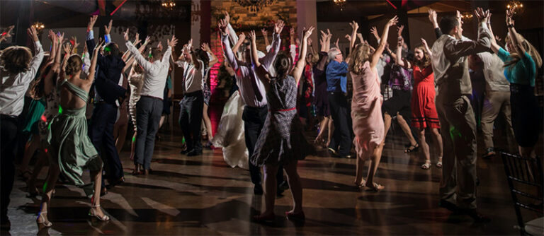 A group of wedding guests doing the YMCA dance. This is the cover photo for the article called best wedding line dance songs for groups.