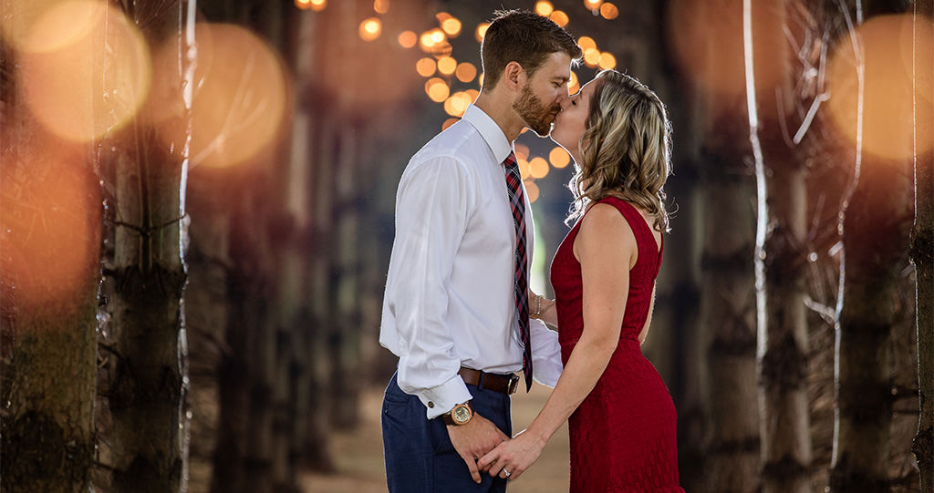 A man and woman kissing each other in the woods