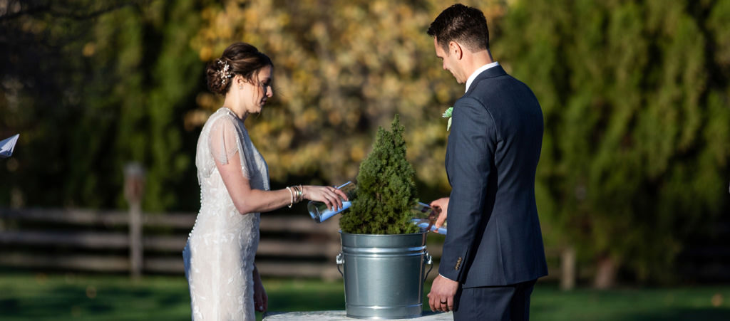 A bride and groom planting a tree in a pot at their tree planting unity ceremony