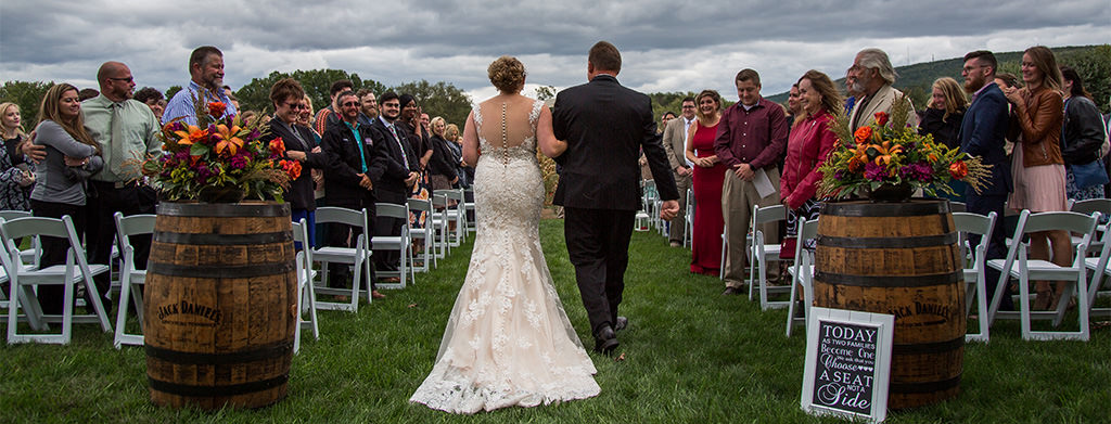 A bride and her dad walking down the aisle at a wedding ceremony.