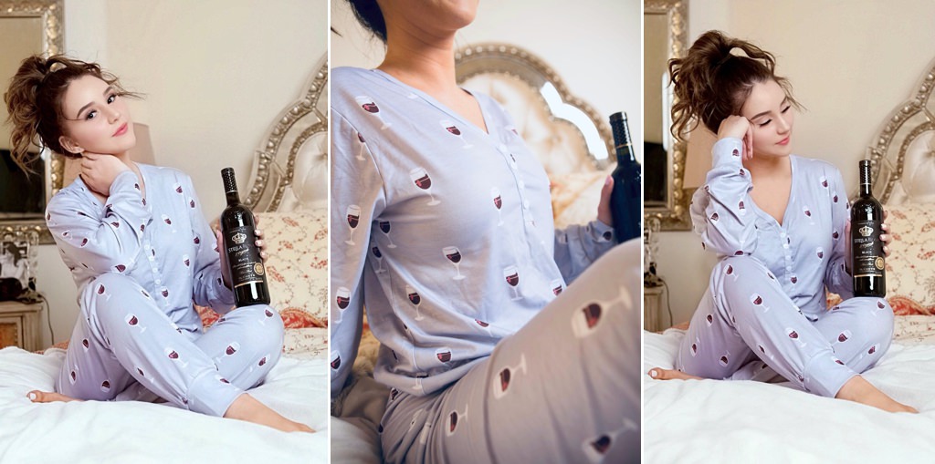 A bridesmaid sitting on a bed with cotton pajamas on that have wine glasses on them.