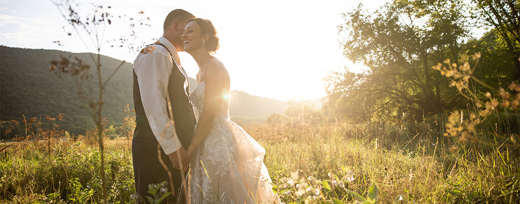 A bride and groom kissing at sunset