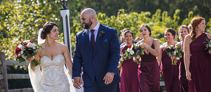 A bride and groom walking. This is the cover photo for the article names wedding day essentials list.