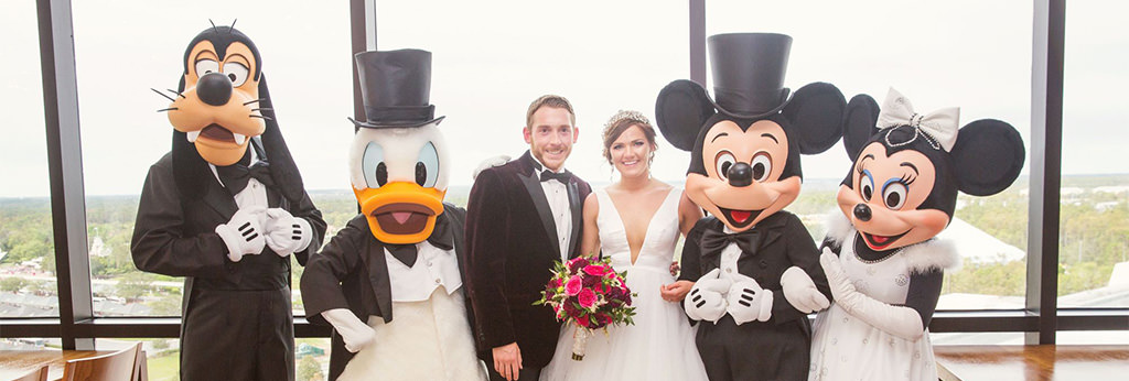 A bride and groom posing with Disney characters