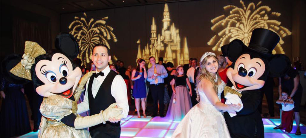 A bride and groom dancing with mickey mouse and minnie mouse. This is for the article called best Disney wedding songs