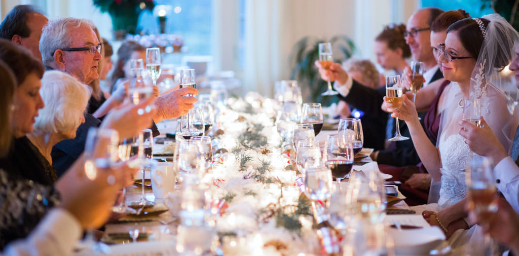 A group of wedding guests raising their glasses for a toast during dinner at the reception