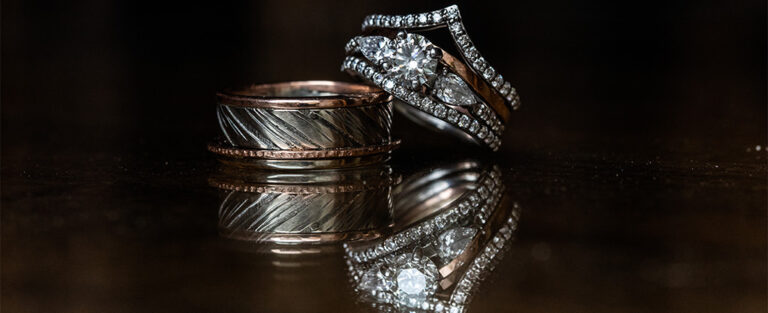 A really awesome wedding band for the groom sitting on a table with the bride's wedding ring.