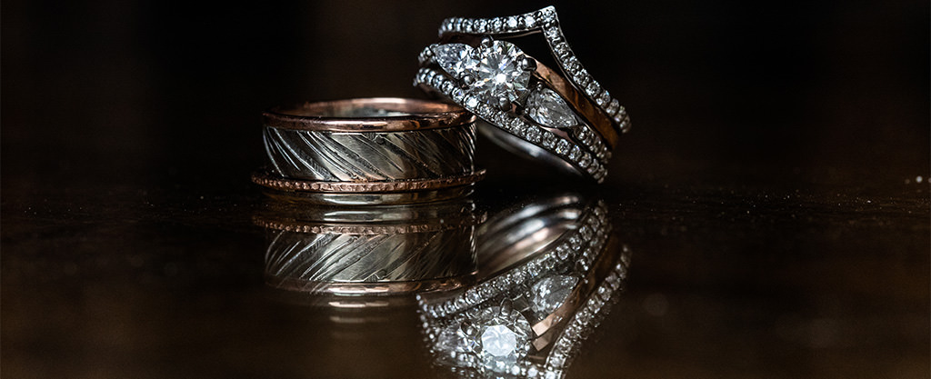 A really awesome wedding band for the groom sitting on a table with the bride's wedding ring.