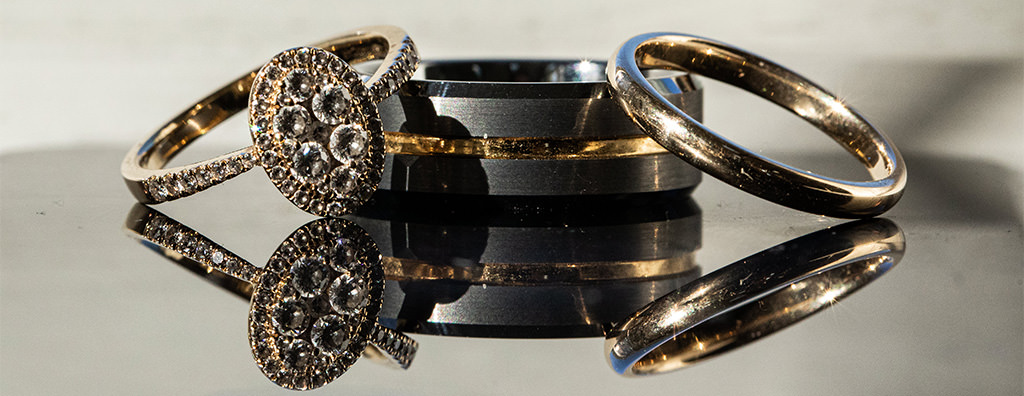 A cool looking titanium wedding band for a man on a table with the bride's ring