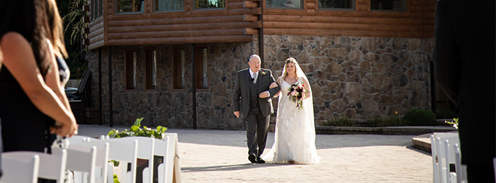 A bride walking down the aisle with her dad. This is the cover photo for the articles called do you wear your engagement ring down the aisle.