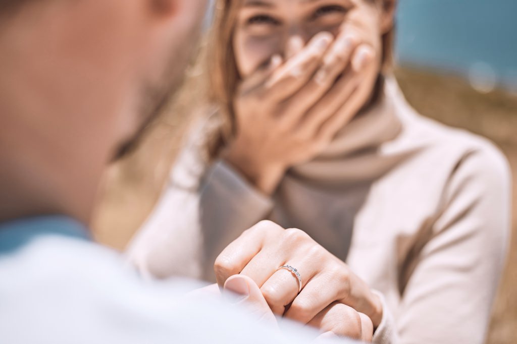 A bride acting surprised when her partner proposed to her with an engagement ring.