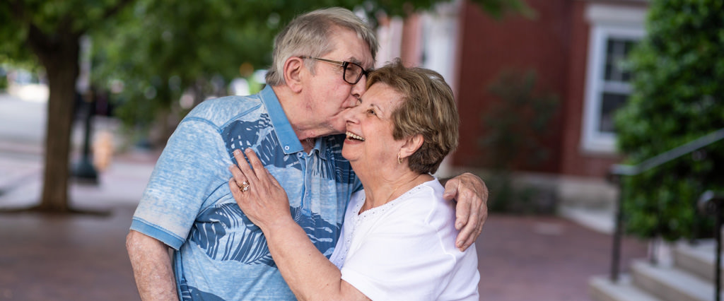 An adorable old couple giving each other a kiss