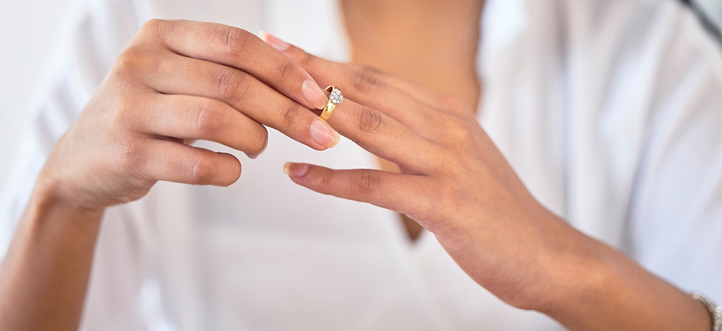 A woman putting on an engagement ring that is too big for her finger. This is for the article called what if my engagement ring is too big or loose.