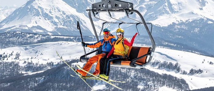A couple riding in a ski lift together. This is the cover photo for the article called best outdoor activities and date ideas for adventurous couples.
