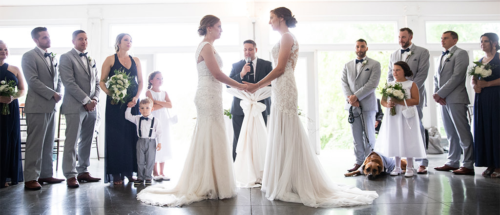 A same-sex wedding ceremony taking place with two brides saying their vows.